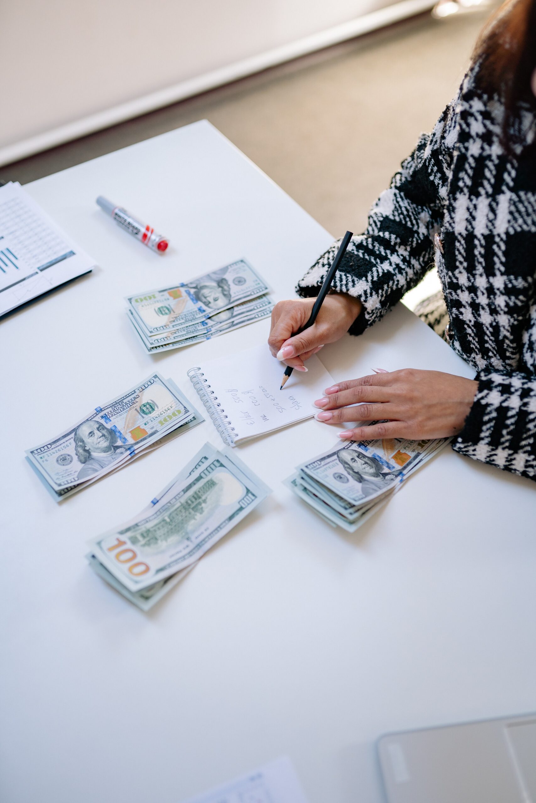 Hombre haciendo un presupuesto en una hoja de papel con montones de dinero a su alrededor