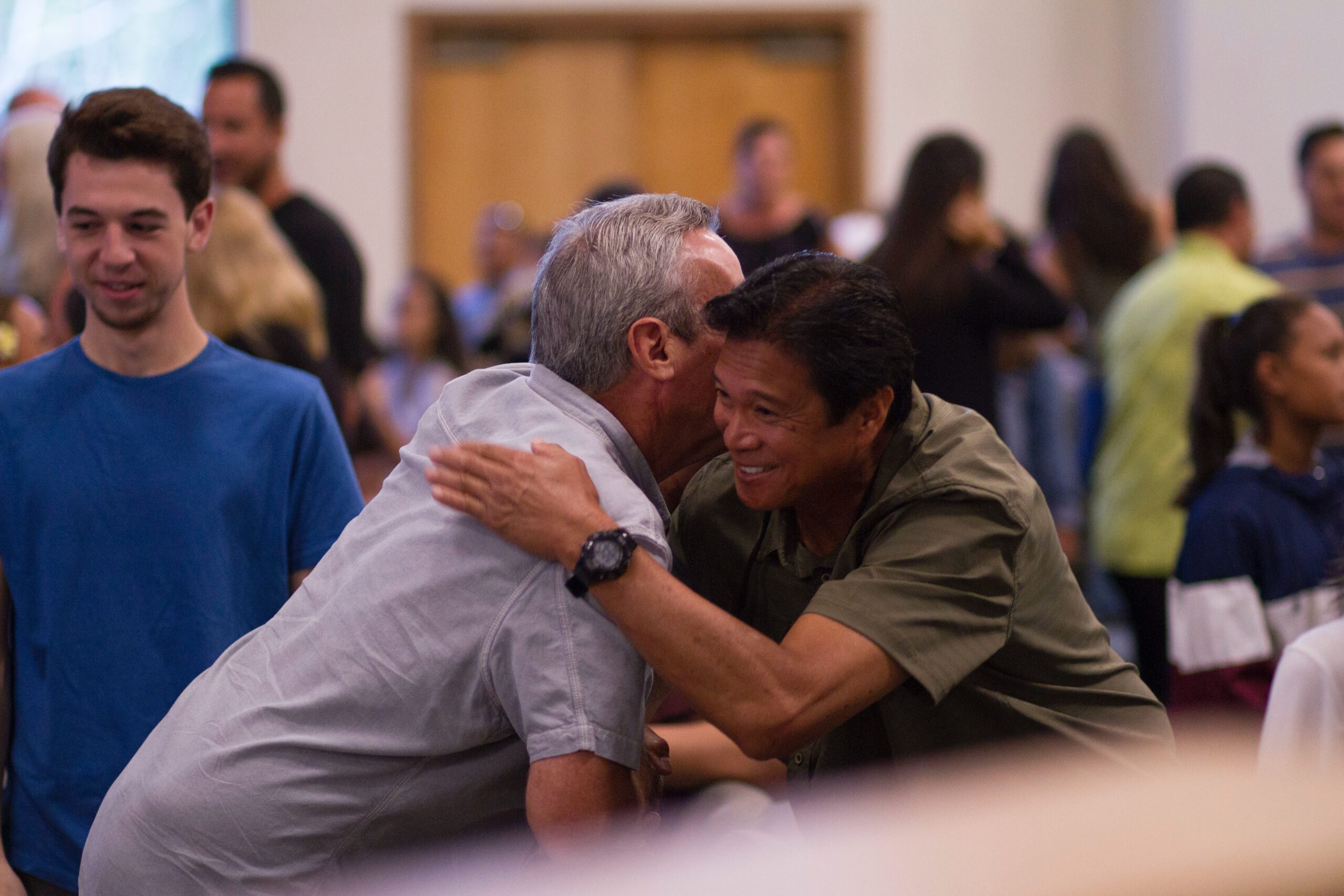 Two older asian men smiling and hugging eachother