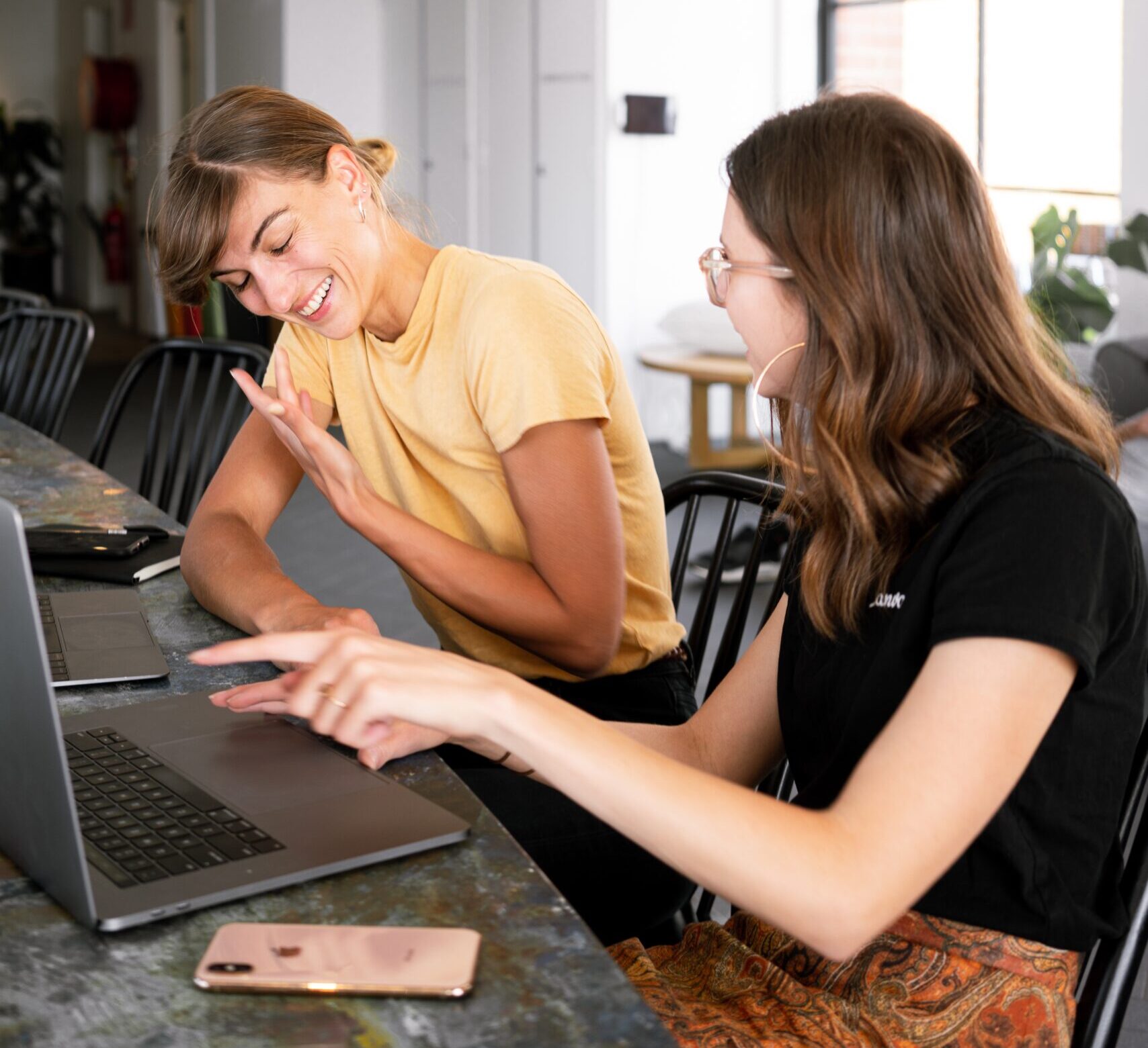 Dos mujeres charlan y ríen mientras miran juntas la pantalla de un ordenador